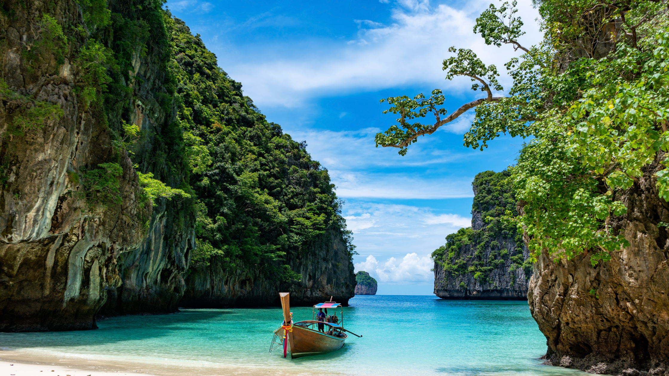 Scenic beach in Thailand with turquoise waters and towering limestone cliffs, showcasing the natural beauty of exploring Thailand’s coastal landscapes.