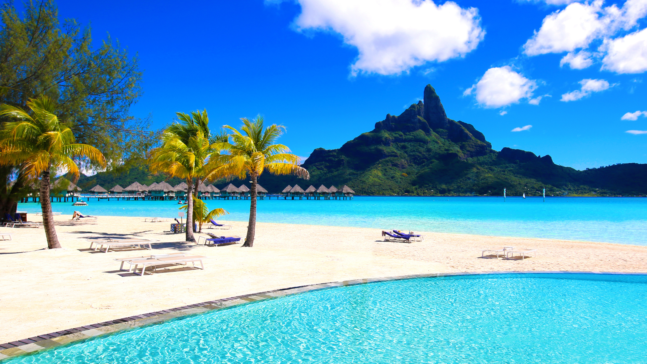 Bora Bora travel guide – A breathtaking view of Bora Bora’s pristine beach with crystal-clear turquoise waters, white sand, and lush tropical scenery