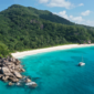 "A breathtaking beach in Seychelles travel guide with soft white sand, turquoise waters, and lush green palm trees under a clear blue sky.