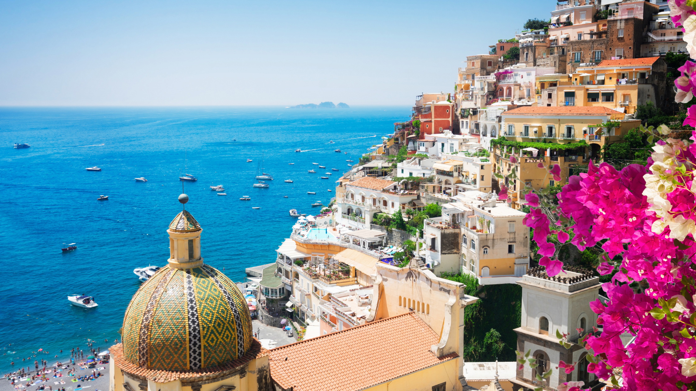 A breathtaking view of the Italian coastline with turquoise waters, rugged cliffs, and colorful seaside villages in the distance